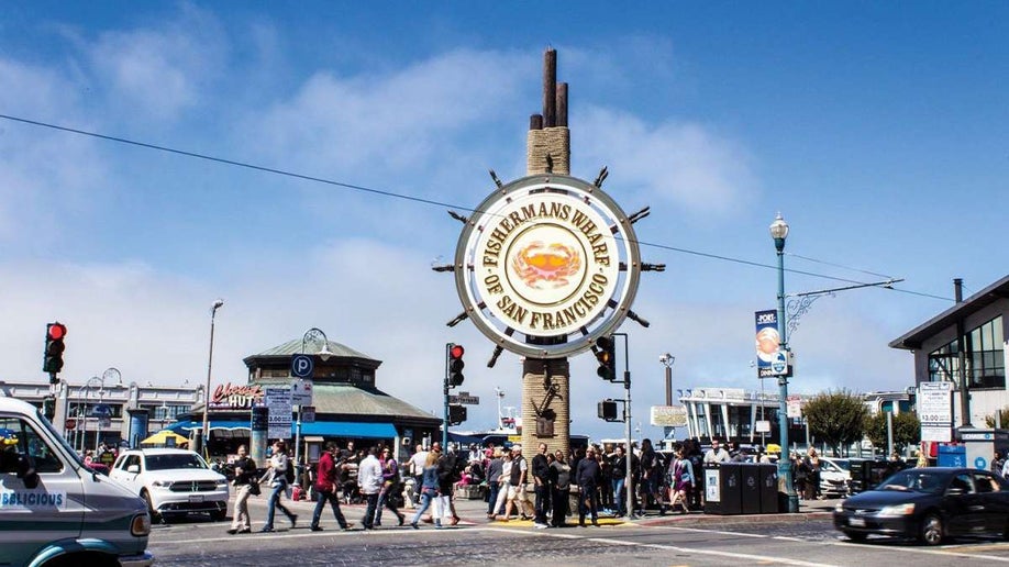 close up of Fisherman's Wharf sign with crowds of people walking through the streets in San Francisco, California, USA