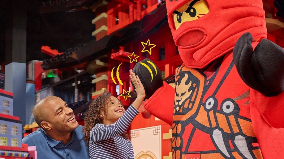 Child and her dad high-fiving a LEGO Ninja at the Legoland Discovery Center in Chicago, Illinois