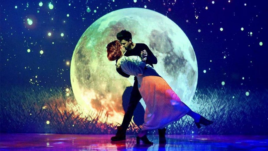 Man and women kissing posed in front of a large moon background with lots of colors and a night sky at the Museum of Dream Space in Las Vegas, Nevada
