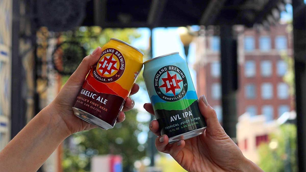 Close up photo of two different types of been in cans cheering from Highland Brewing in Asheville, North Carolina, USA