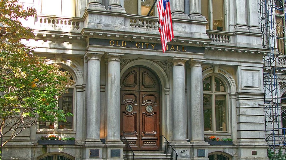Close up photo of the front doors of Old City Hall with a flag hanging above it in Boston, Massachusetts, USA