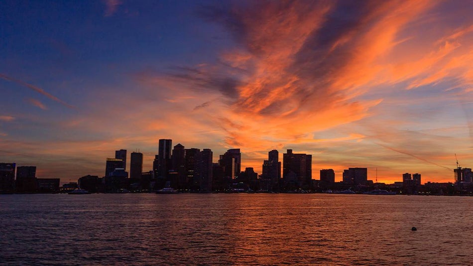 Wide shot of the harbor at sunset with a clear outline of the building in Boston, Massachusetts, USA