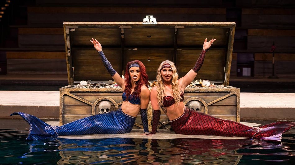 Two mermaid actors laying in front of a giant treasure chest at Pirates Voyage Dinner and Show in Myrtle Beach, South Carolina, USA