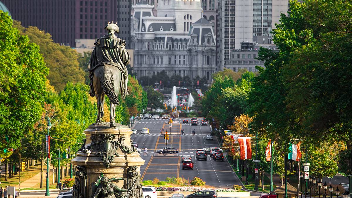 Close up statue of Benjamin Franklin facing away from the camera with Benjamin Franklin Parkway in the background in Philadelphia, Pennsylvania