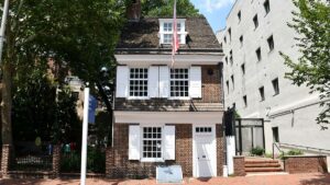 The front of the historic Betsy Ross house in the daylight with a flag flying on the front of it in Philadelphia, Pennsylvania
