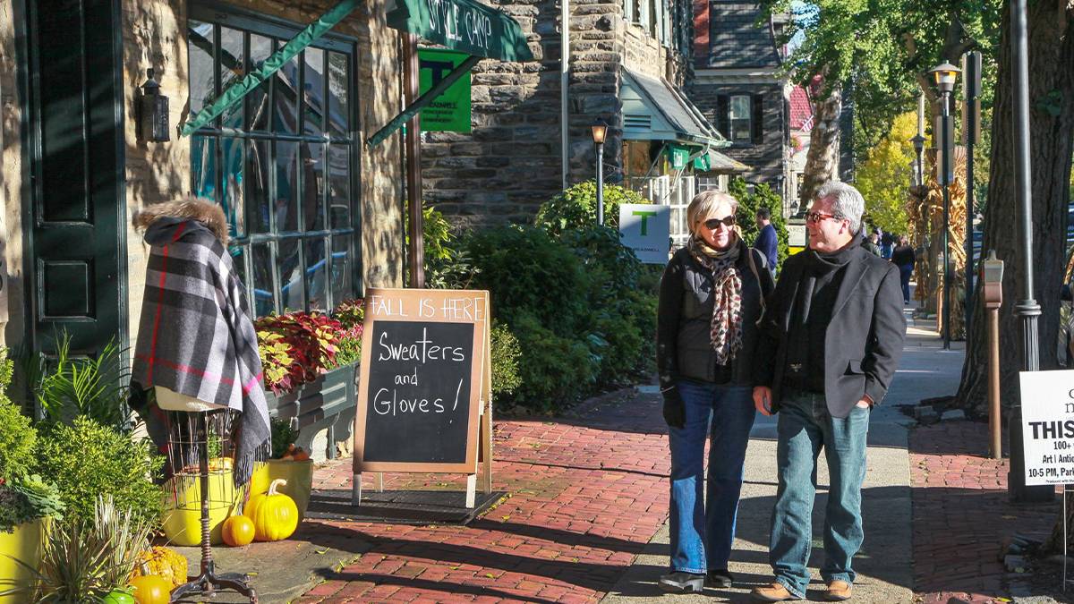 An older couple walking past a store in the Chestnut Hill are of Philadelphia, Pennsylvania, USA
