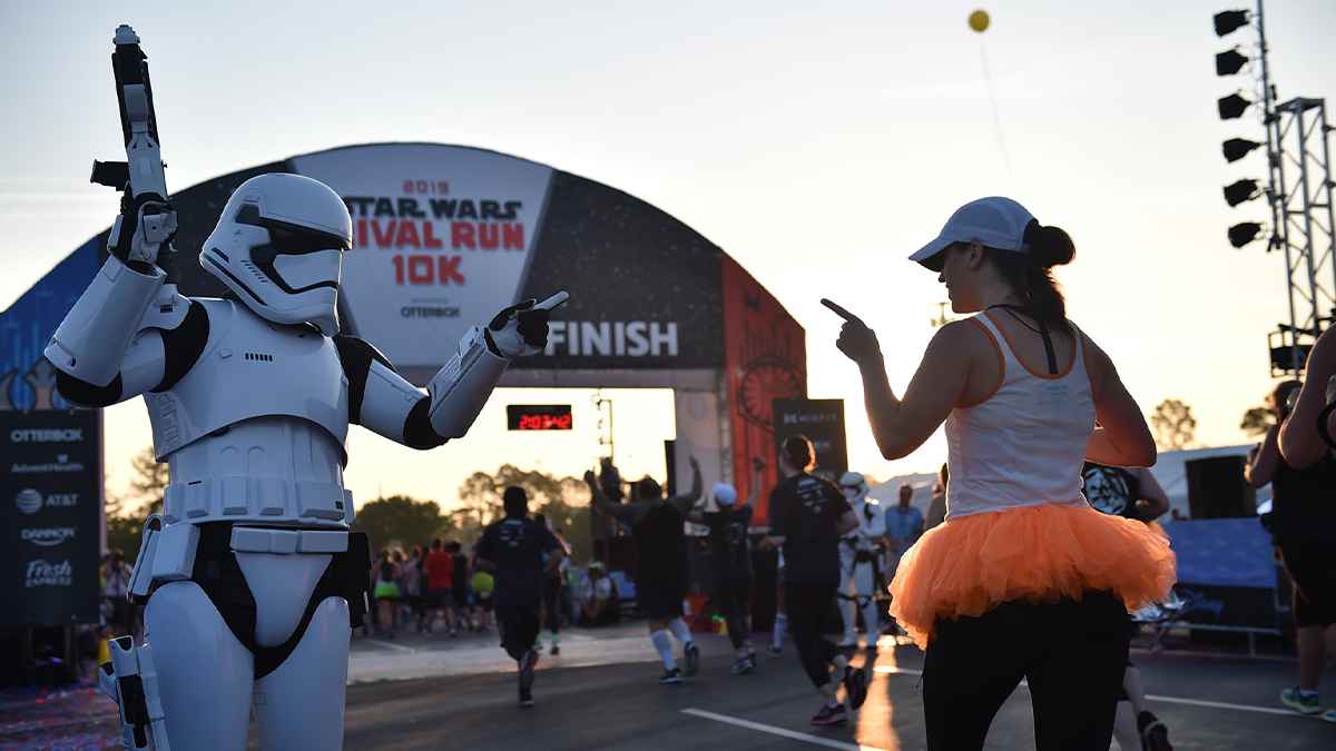 Stormtrooper and runner pointing at each other with the finish line for the Rival Run 10k behind them