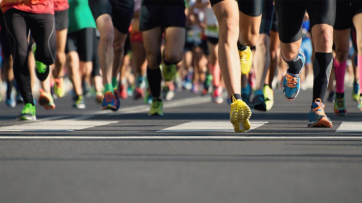 Shot of several peoples feet as they are running a marathon on black top.