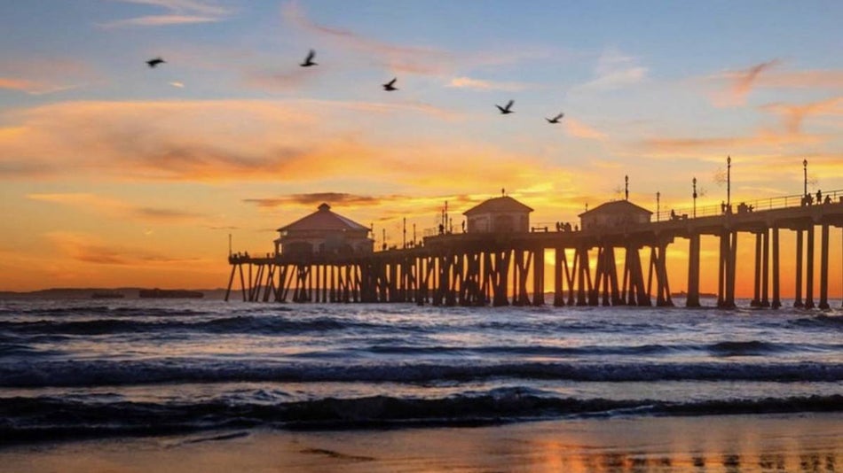 Wide shot of the pier at sunset set at Huntington Beach in Los Angeles, California, USA
