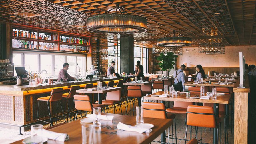 A dining room with a bar and hightop tables with small leather chairs and big round ligh fixtures hanging from the ceiling at Casi Cielo in Atlanta, Georgia, USA