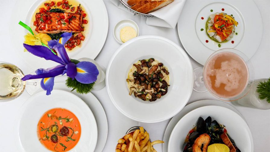 Looking down at a table full of different dishes on white plates on a white table cloth at Le Bilboquet in Atlanta, Georgia, USA