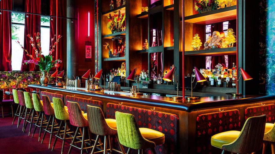 A bar that has lots of bright colors, blues, greens, and pinks, with green reflective chairs sitting at the bar at Ruby Chow’s in Atlanta, Georgia, USA