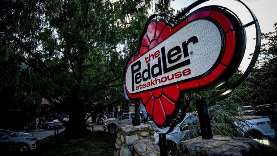 Close up photo of the red, black, and white sign for the The Peddler Steakhouse in Gatlinburg, Tennessee, USA