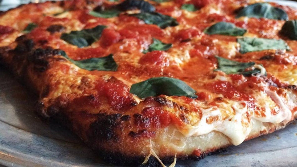Close up view of a sourdough pizza with tomatoes, cheese and spinach from Ops in NYC, New York, USA