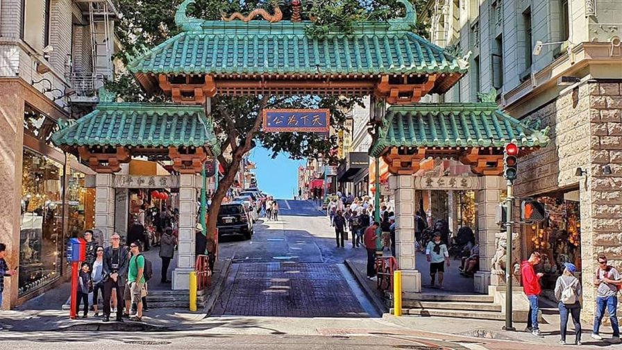 Chinese style archway with green and copper roofs called Dragon Gate surrounded by people in San Francisco, California, USA