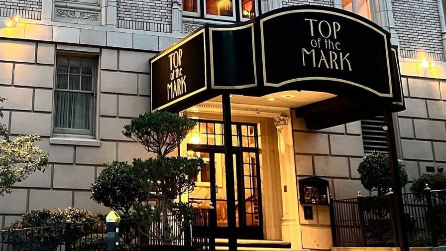 View of the entrance to Top of the Mark, a black awning with gold accents on a white brick building in San Francisco, California, USA