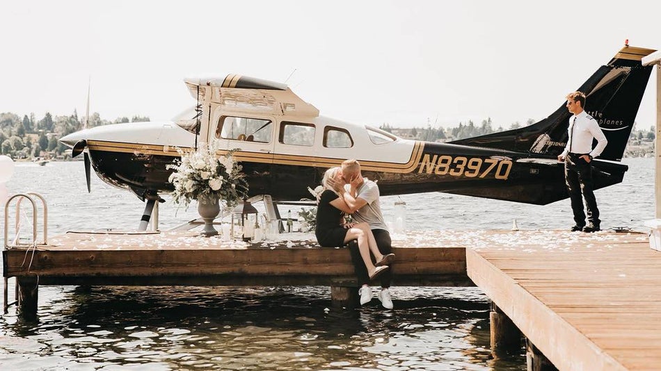 Couple kissing in front of a seaplane with a large bouquet of flowers next to them sitting on the dock in Seattle, Washington, USA