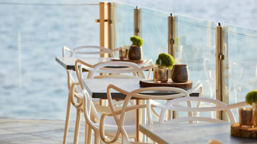 Three tables with glasses on them in the outdoor dining area of Six Seven Restaurant up against a glass railing in Seattle, Washington, USA