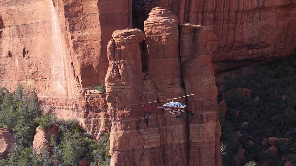 Red and white helicopter flying down in the the rock formations on the Hog Wild Helicopter Tour of Sedona, Arizona, USA