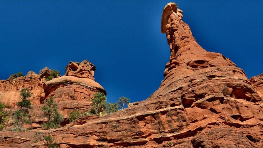View looking up at the rock formations that make the Sedona Vortex with a blue sky behind them in Sedona, Arizona, USA