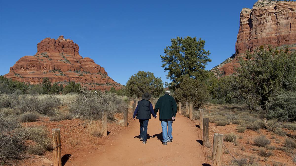 Couple holding hands and hiking through Arizona's Red Rock Country in Sedona, Arizona, USA