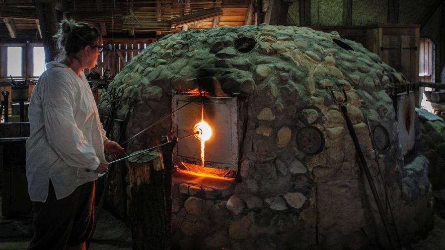 Woman in a white shirt heating glass at the Glasshouse in Jamestown near Williamsburg , Virginia, USA