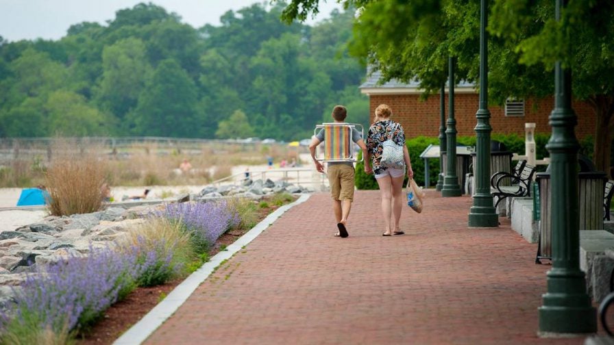 Couple walking on the Riverwalk Landing with their gear for a picnic in Williamsburg, Virginia, USA