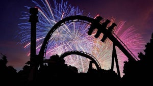 a silhouette of a rollercoaster in front of a fireworks display