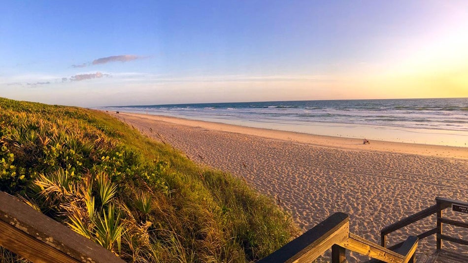 wide shot of beach with sand dunes at sunrise