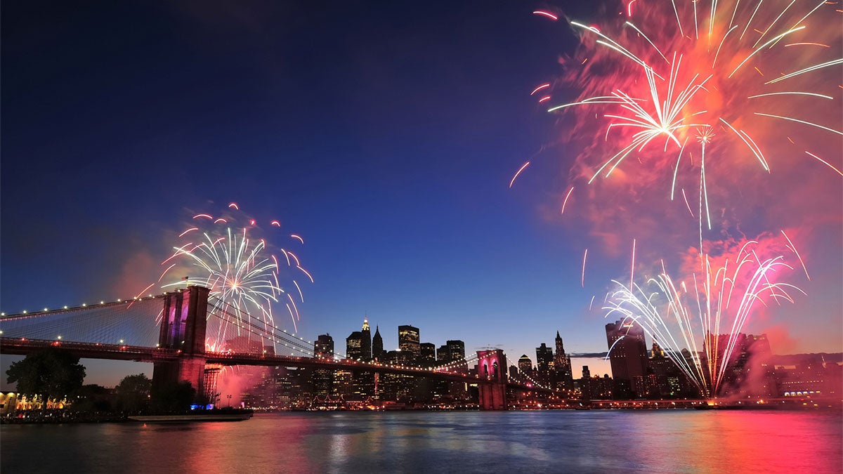 fireworks over bridge and buildings at night at Circle Line Cruise Sightseeing and Firework Cruises in New York City, New York, USA