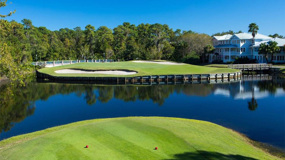 golf course with sandpits, water, trees, and establishment in distance at Disney's Lake Buena Vista Golf Course in Orlando, Florida, USA