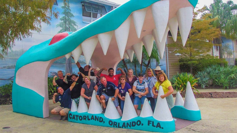 people posing in gator mouth statue at Gatorland in Orlando, Florida, USA