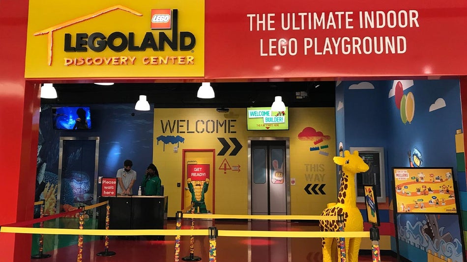 entrance to LEGOLAND with giraffe figure made of lego and two staff in booth in New Jersey, USA