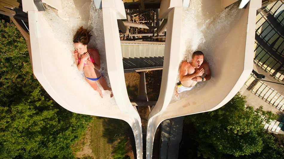 top view of people slidding down tall slide with trees in bottom at Fire Tower Falls in Dollywood Splash Country, Pigeon Forge, Tennessee, USA