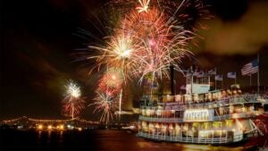 boat with american flags on water with fireworks in sky at Fourth on the River in New Orleans, Louisiana, USA