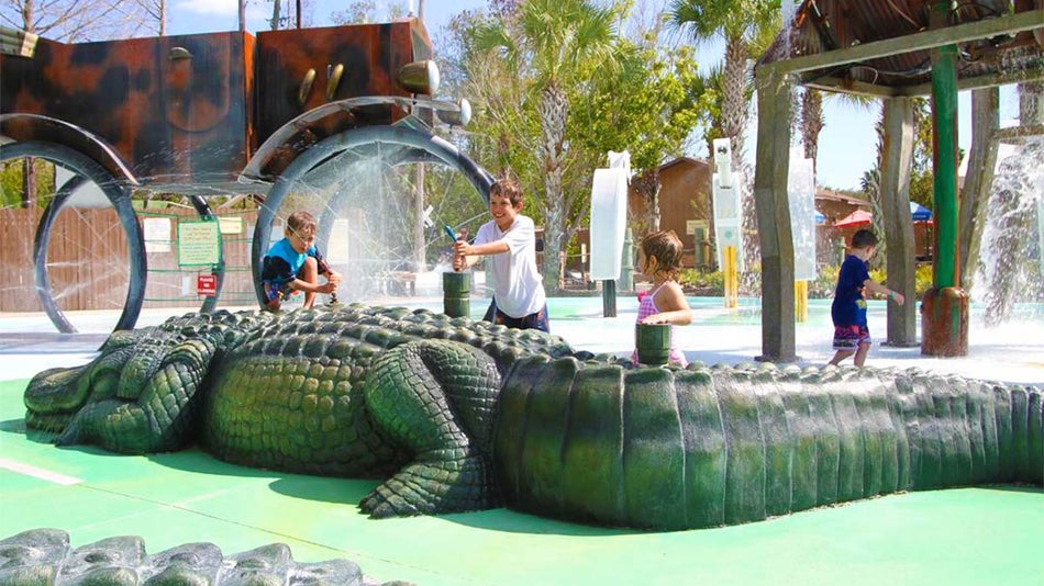 children playing with sprinklers at Gator Gully Park during sunny day at Gatorland in Orlando, Florida, USA