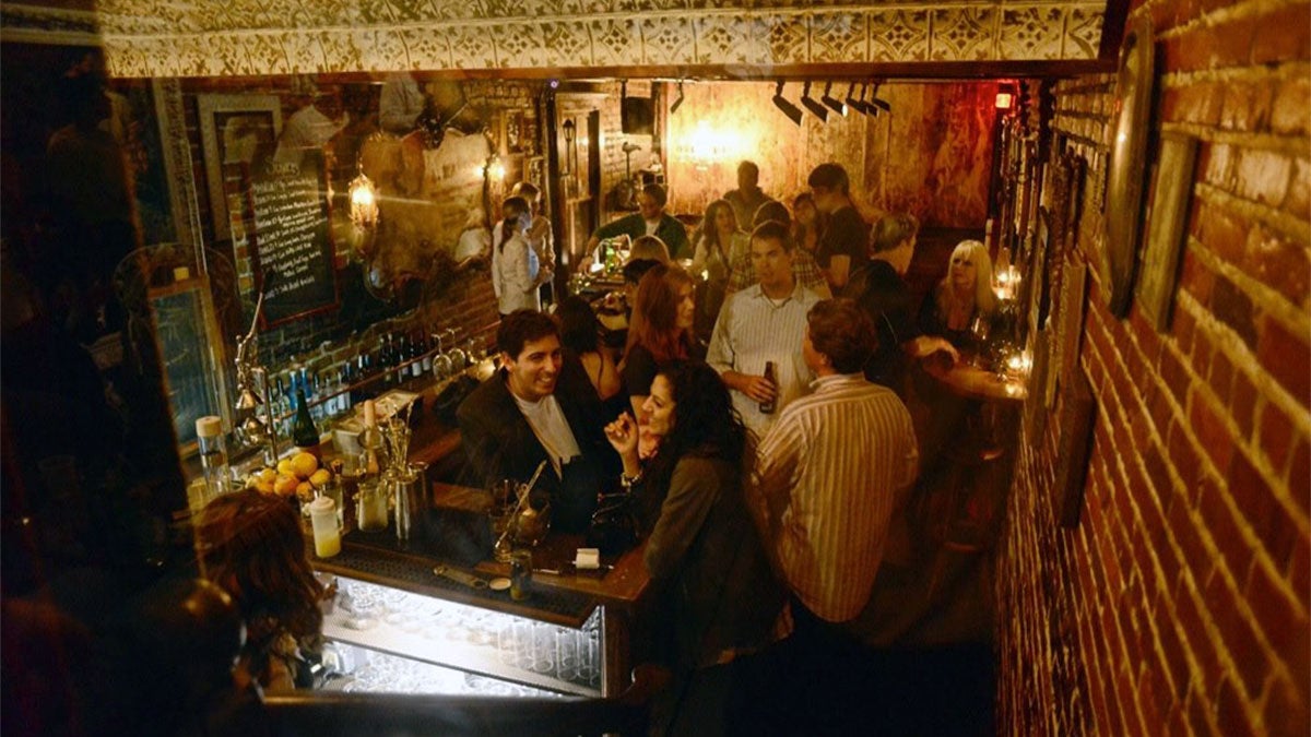 people chatting and enjoying drinks around bar at establishment with brick walls and tiles at Hanson's Shoe Repair Speakeasy in Orlando, Florida, USA