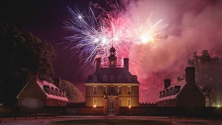 colorful fireworks over historical building surrounded by trees at Lights of Freedom event in Williamsburg, Virginia, USA