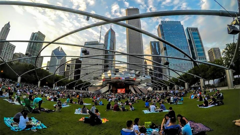people seated on grass at Millennium Park for Summer Music Series event during daytime with buildings in background at Chicago, Illinois, USA