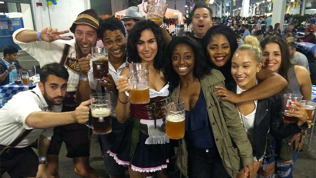 group of friends posing for photo while holding beer mugs and cups at Oktoberfest by the Bay in San Francisco, California, USA