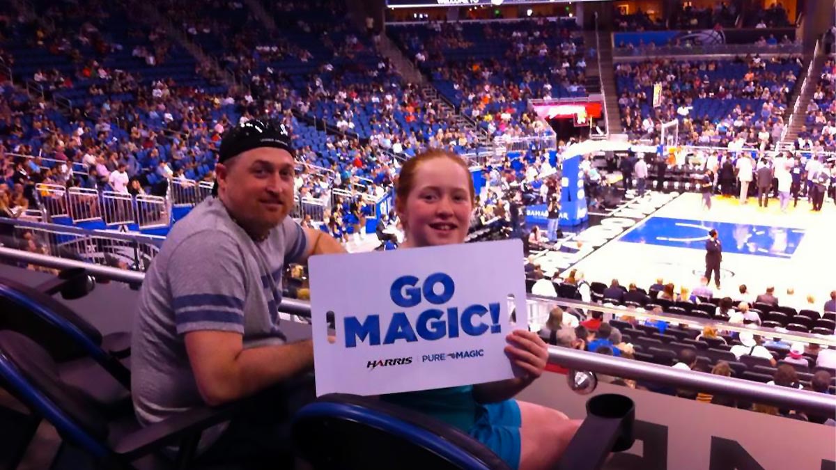 father and daughter holding up sign during Orlando Magic Basketball Game in Orlando, Florida, USA