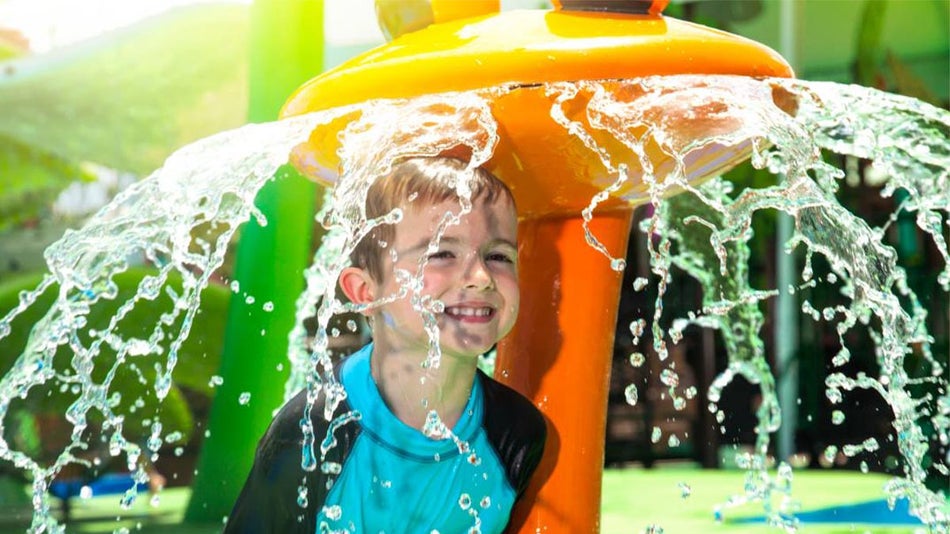 smilling child under splash pad with running water at The Florida Aquarium in Tampa, Florida, USA