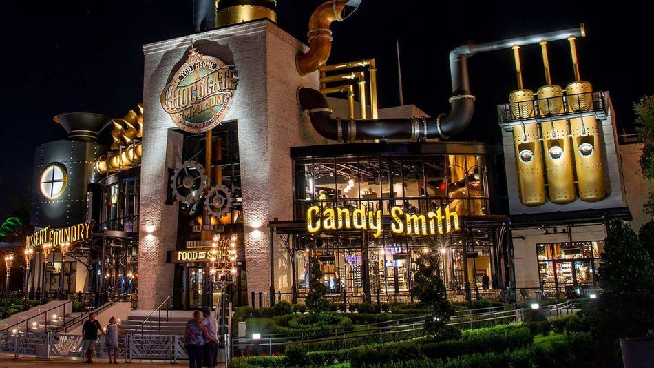 exterior of The Toothsome Chocolate Emporium and Savory Feast Kitchen at night with people walking along entrance in Orlando, Florida, USA