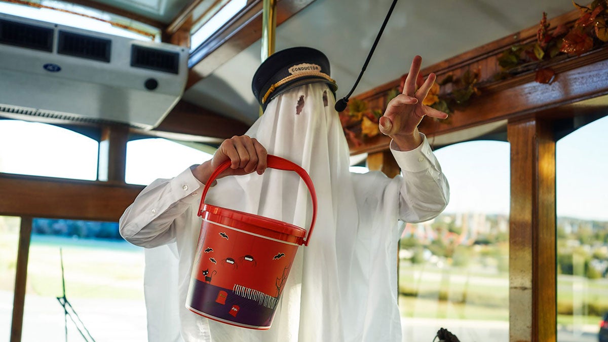 man with conductor hat in ghost cotume holding bucket and talking in microphone for Trick or Treat Trolley at Hersheys Chocolate World in Philadelphia, USA