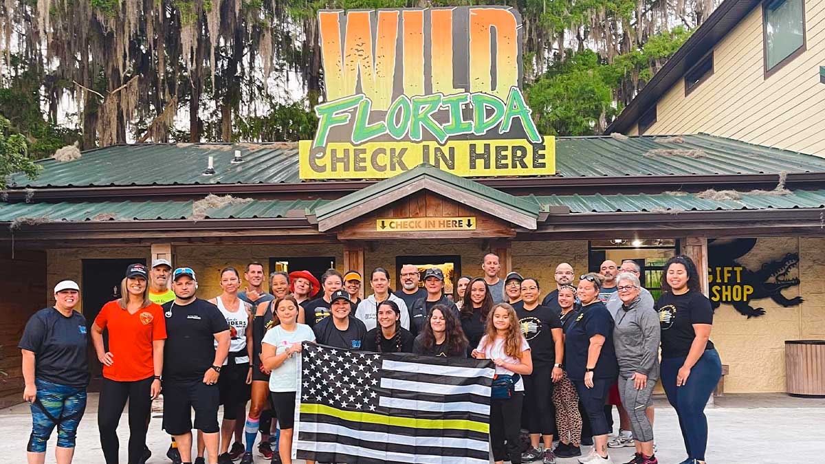 group of people holding flag posing for photo in front of Wild Florida Airboat Tours and Gator Park in Orlando, Florida, USA