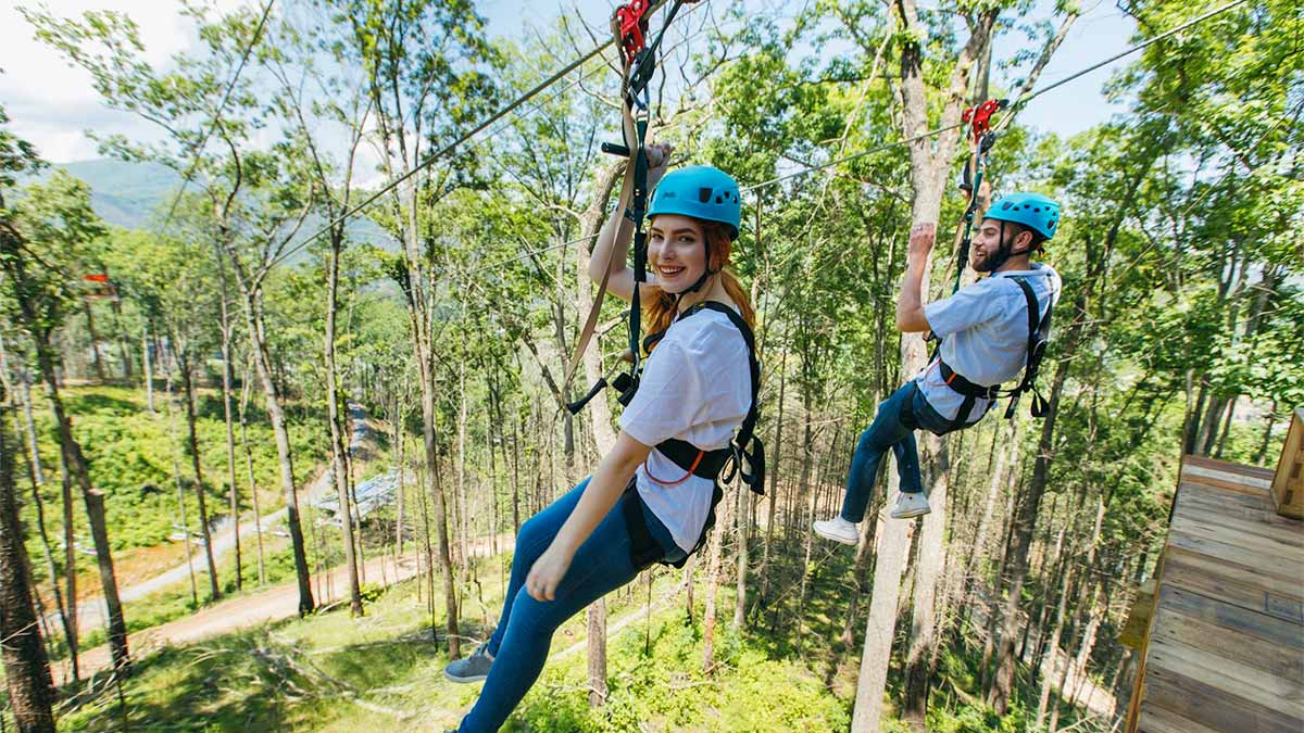 couple on zipline with trees in background at Anakeesta Dueling Zipline in Gatlinburg, Tennessee, USA