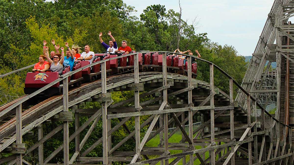 people aboard wooden roller coaster Arkansas Twister surrounded by greenery at Magic Springs in Hot Springs, Arkansas, USA
