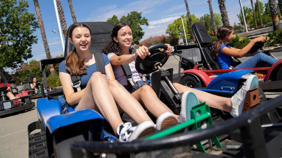 Three girls are having so much fun riding a go-kart.