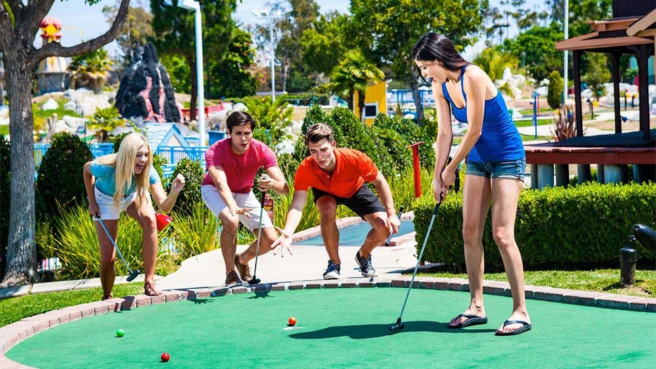 four friends playing mini golf during sunny day at Boomers Mini Golf course at Boomers Livermore in San Franciso, California, USA