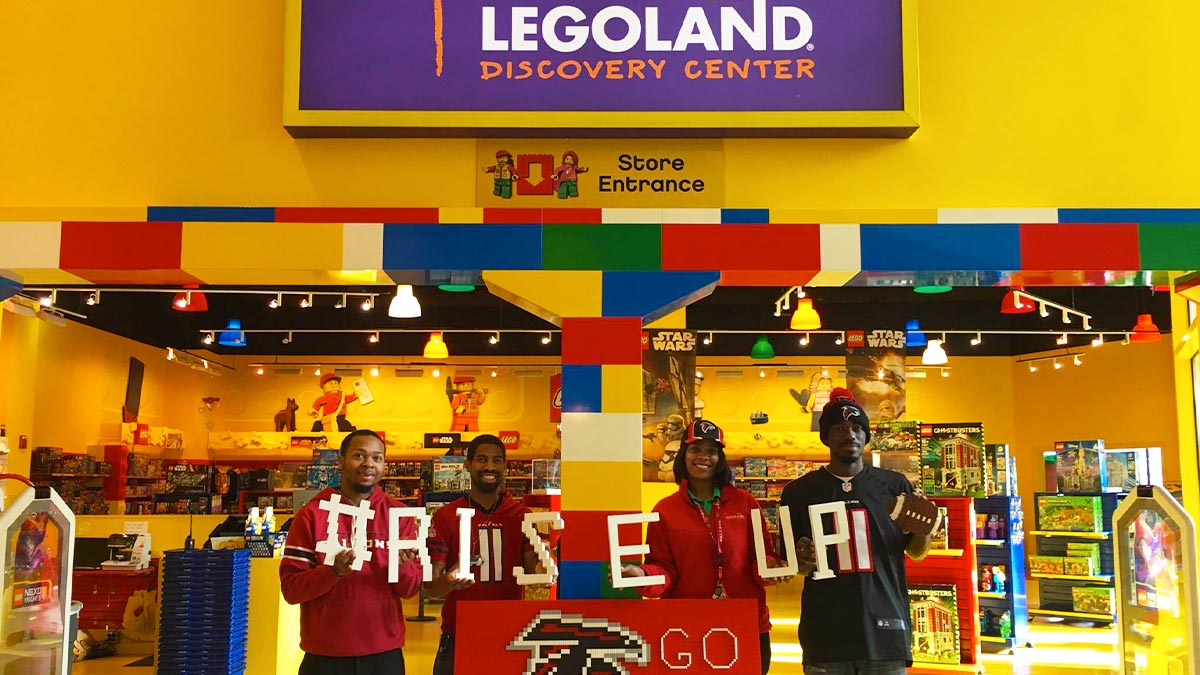 people holding up letters made up of lego blocks at